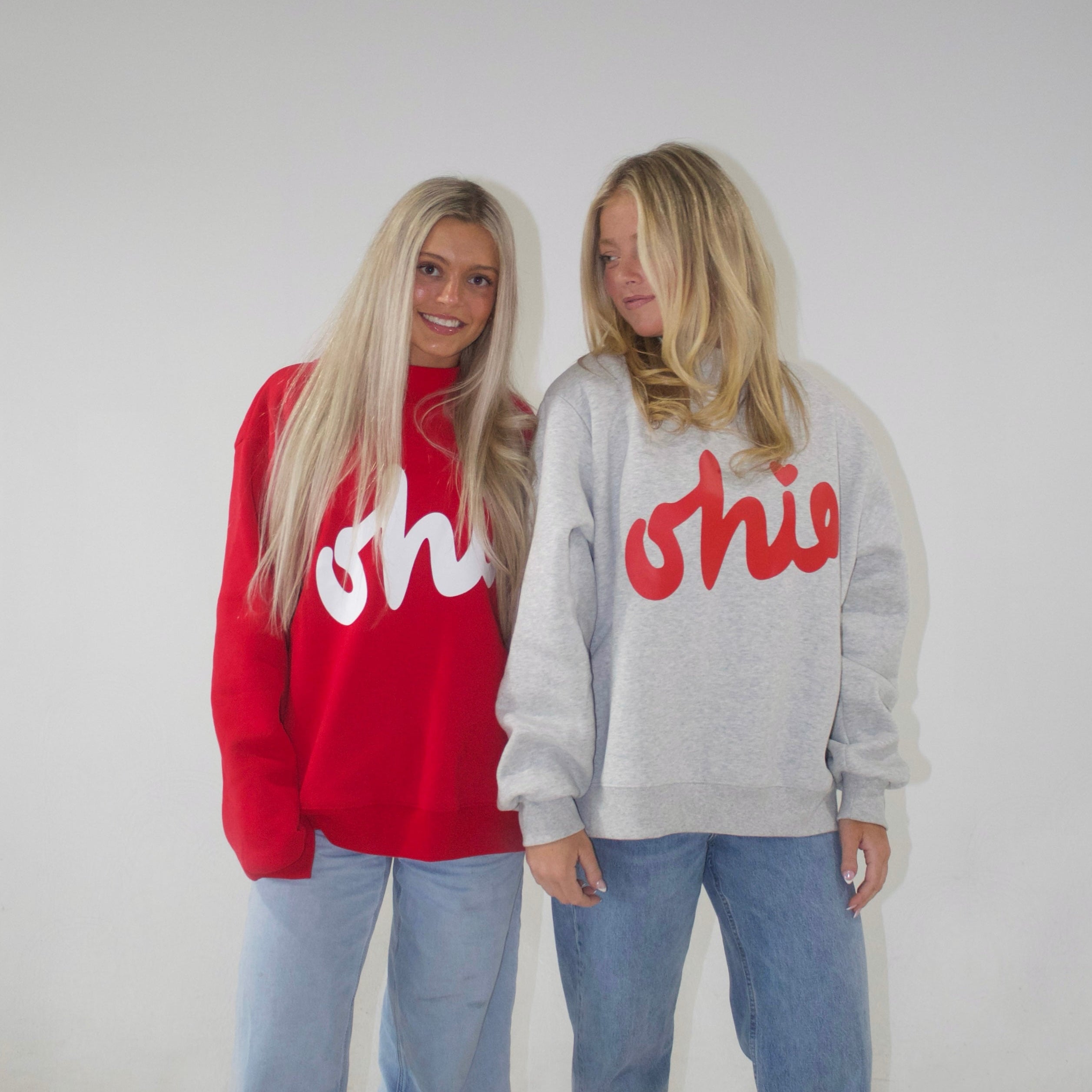 Two people wearing red and gray sweatshirts with 'Ohio' printed on them, standing against a plain background.